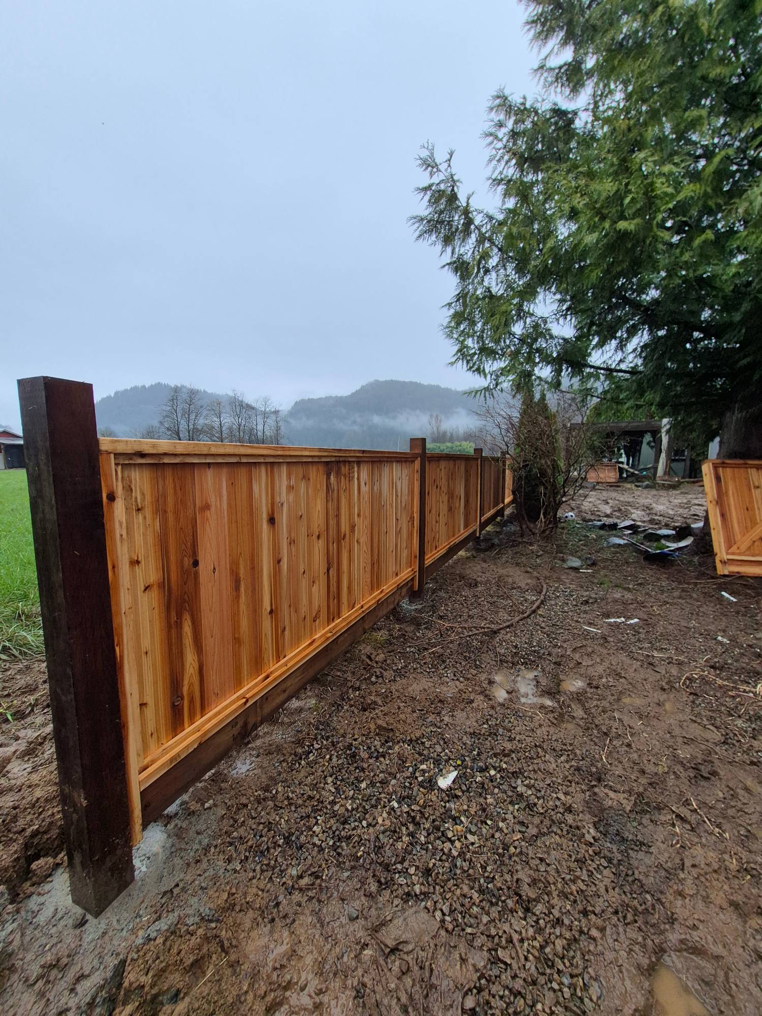 Cedar privacy fence along a field with mountains behind