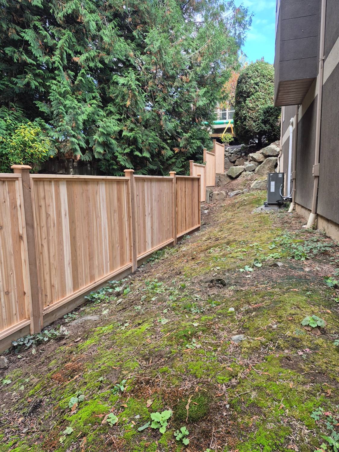 Cedar privacy fence stepping up a slope beside a house